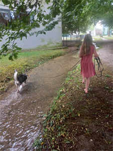 ein Mädchen, das mit einem Hund auf einem Pfad spazieren geht